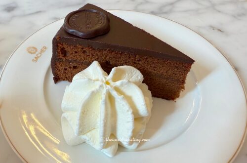 Traditional Sachertorte is an Austrian chocolate cake featuring apricot jam and chocolate glaze, served here with whipped cream